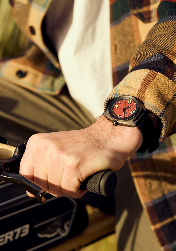 Young adult riding a bike while wearing the Nixon Clutch 42 analog watch