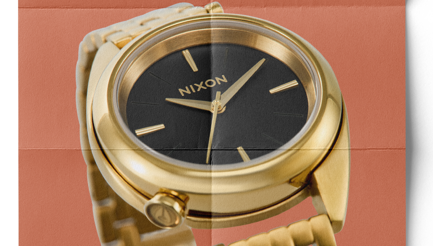 Gold and Black Nixon Eddy watch on folded magazine paper.